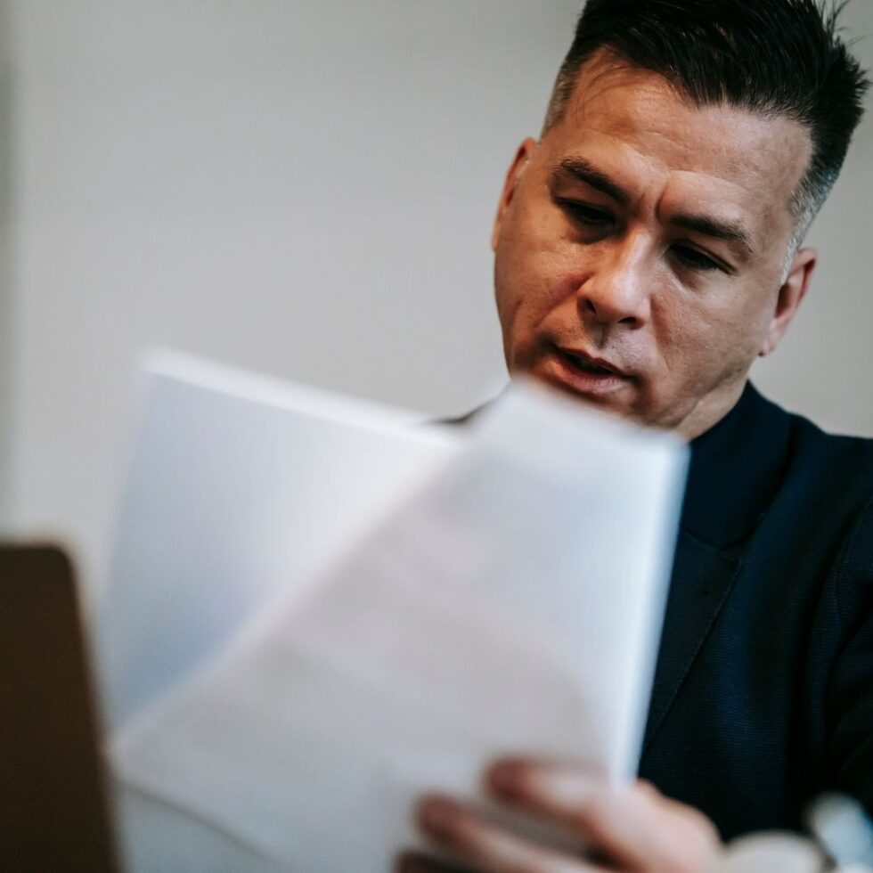 Homme examinant des documents devant un ordinateur