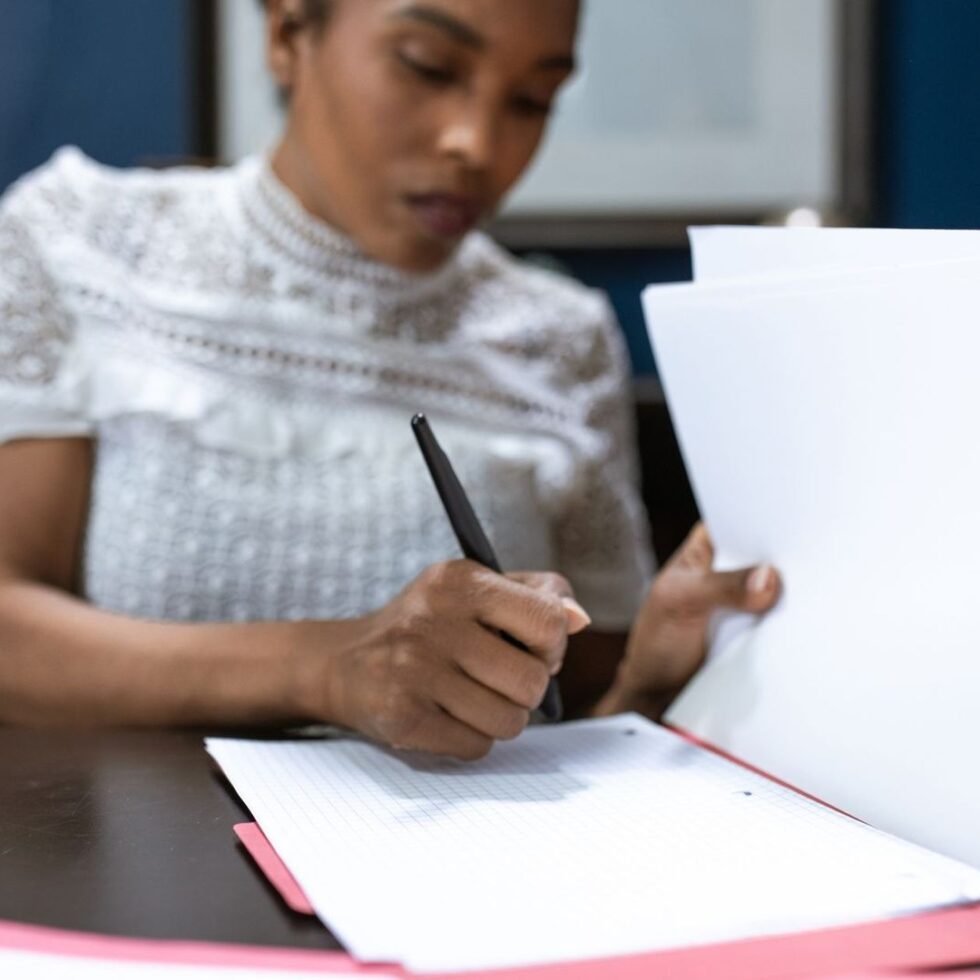 Personne consultant des documents et écrivant sur un formulaire